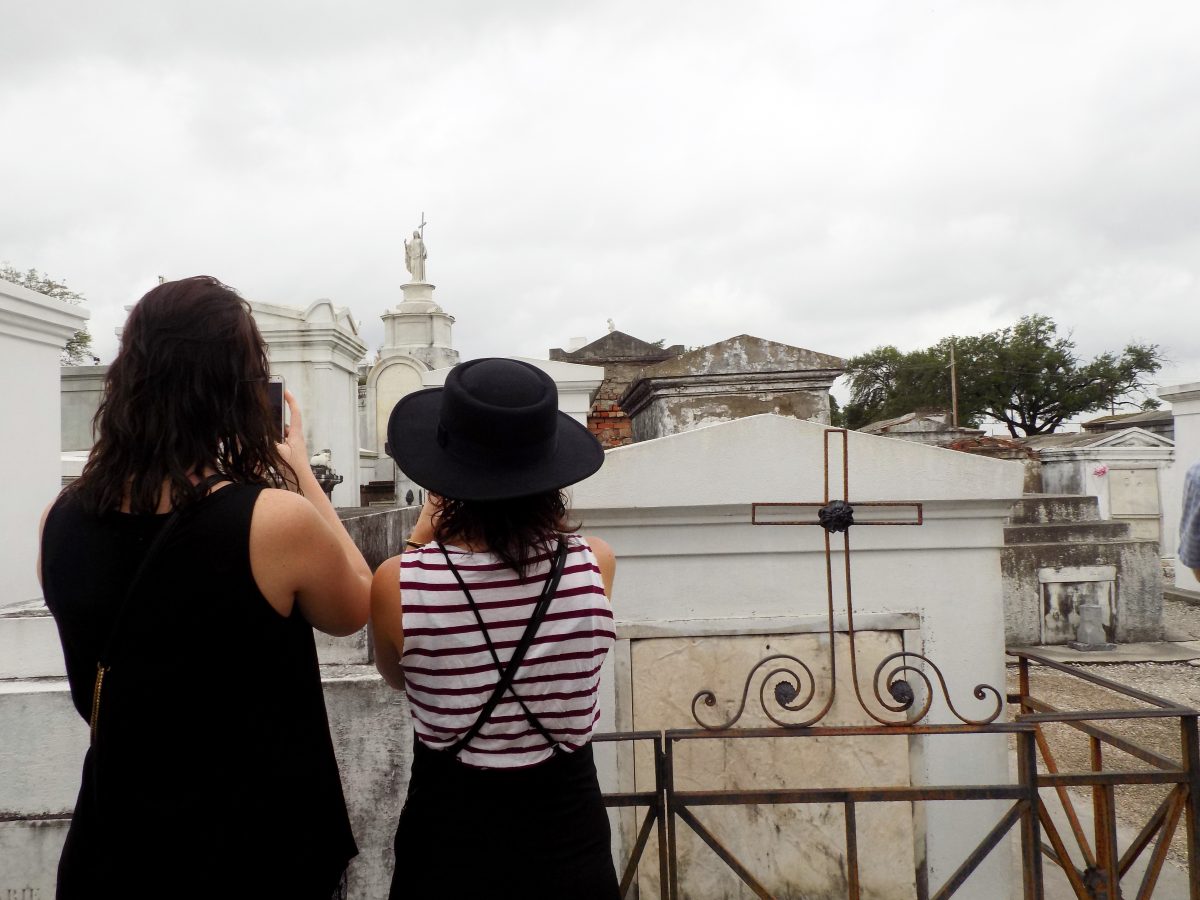 Two women taking pictures of the catacombs in New Orleans on a tour. Joining a tour is a great way to make new friends while solo traveling. 