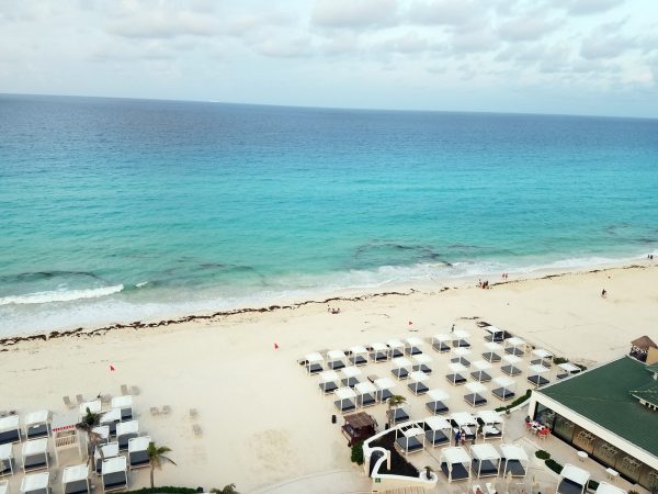 The ocean and beach in front of Sandos Cancun is filled with cabanas and loungers. 