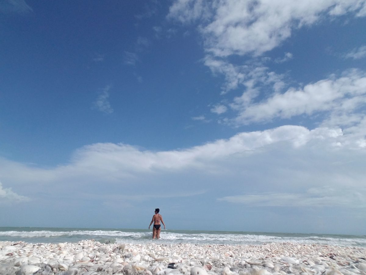Girl standing in the ocean off the coast of the Sanibel Island near Fort Myers, Florida